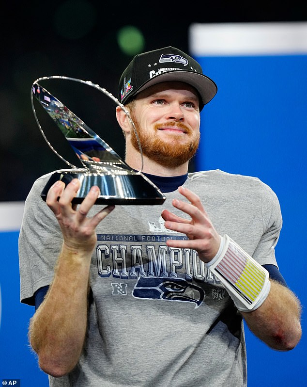 Seattle Seahawks quarterback Sam Darnold (14) holds the NFC Championship trophy
