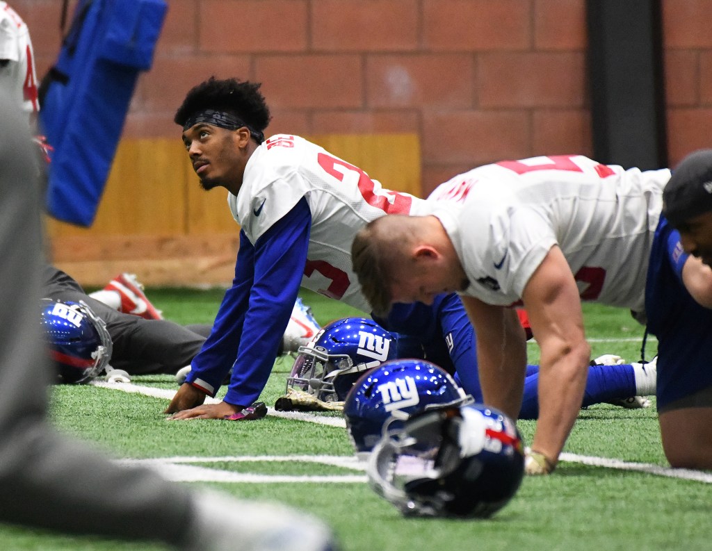 New York Giants defensive back Sam Beal #23 and other players stretch on the ground during practice.
