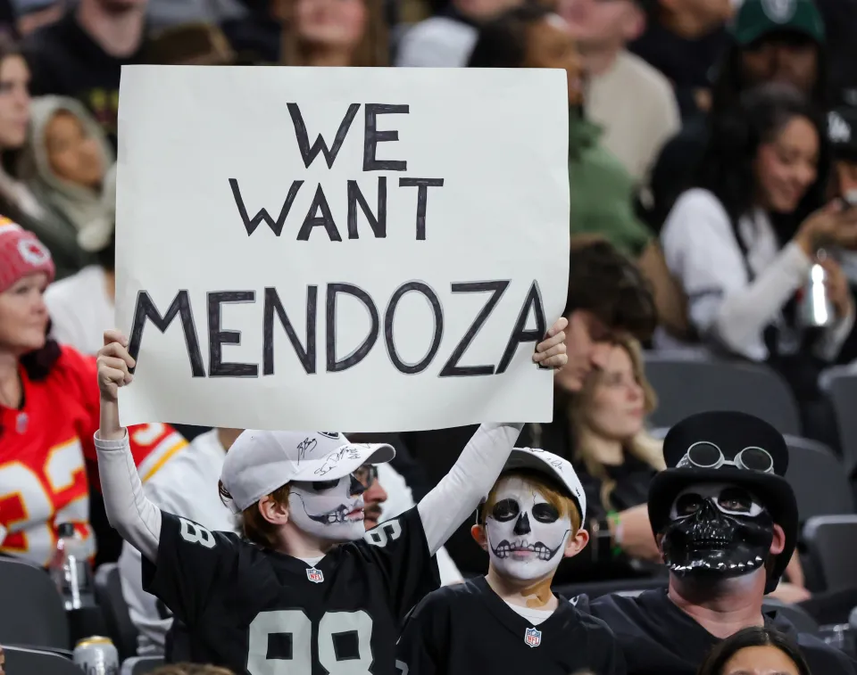 Las Vegas Raiders fan Ezra Kheel (L) of Nevada holds up a sign referencing Indiana quarterback Fernando Mendoza, the 2025 Heisman Trophy recipient, as his brother Alexandros Kheel looks on in the second quarter of the Raiders' game against the Kansas City Chiefs at Allegiant Stadium