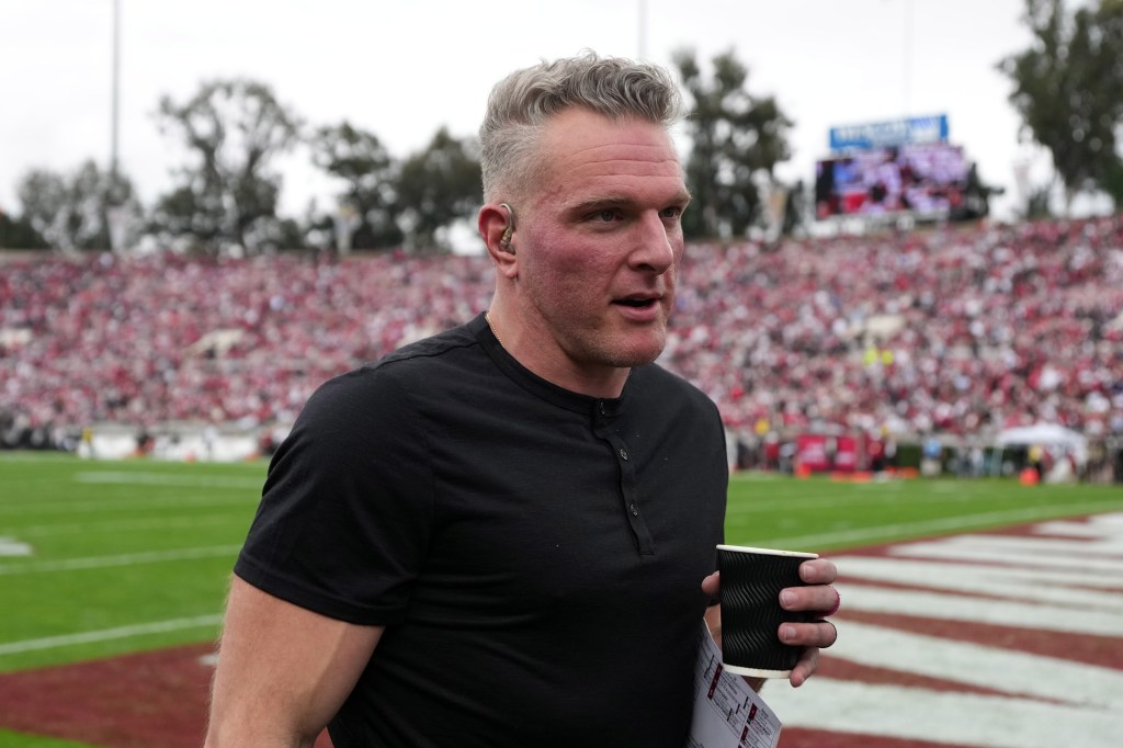 Pat McAfee holding a cup and notes on the field at the Rose Bowl.