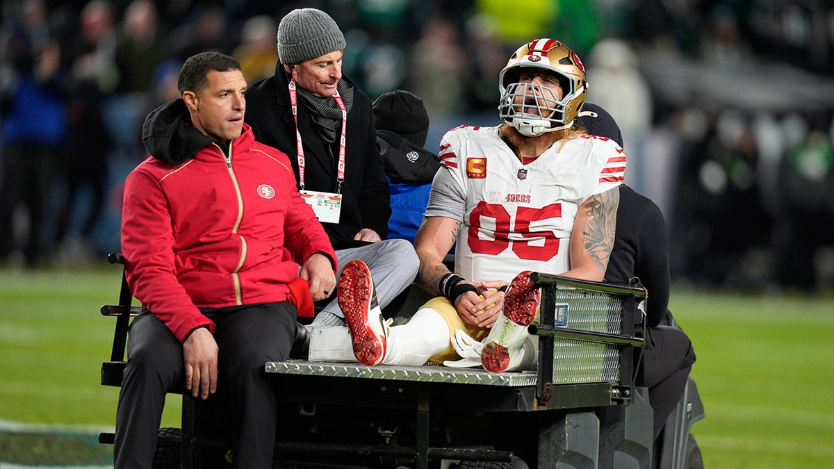 George Kittle sits on the cart