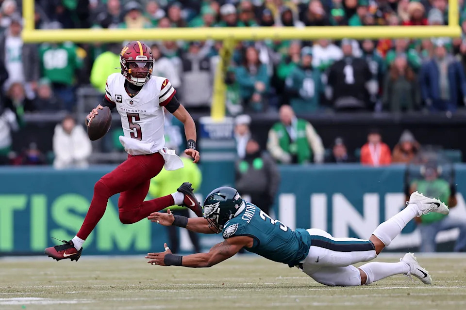 Washington Commanders quarterback Jayden Daniels leaps to avoid the tackle of Philadelphia Eagles linebacker Nolan Smith Jr.
