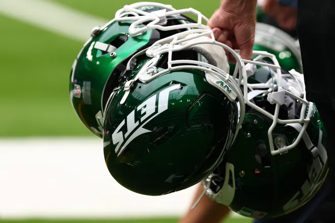 New York Jets helmets are held by staff.