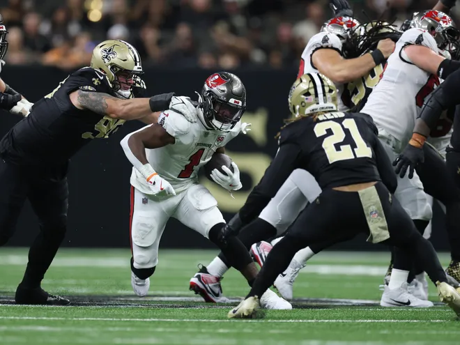 Oct 26, 2025; New Orleans, Louisiana, USA; Tampa Bay Buccaneers running back Rachaad White (1) runs for a gain past New Orleans Saints defensive tackle Bryan Bresee (90) during the second quarter at Caesars Superdome. Mandatory Credit: Stephen Lew-Imagn Images