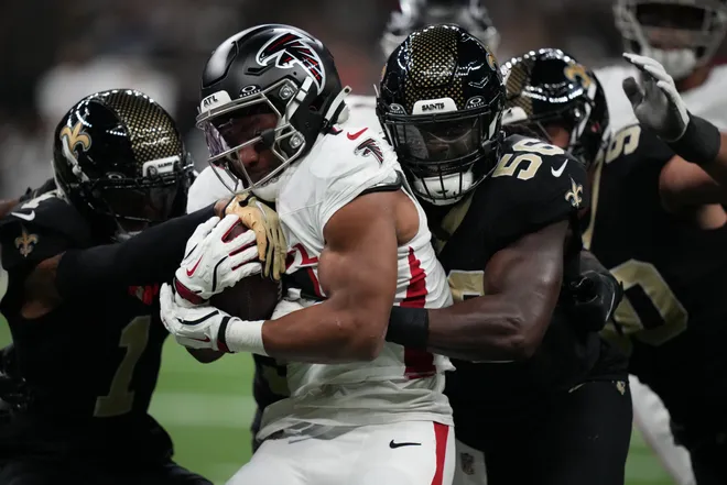 Nov 23, 2025; New Orleans, Louisiana, USA; Atlanta Falcons running back Bijan Robinson (7) carries the ball as New Orleans Saints linebacker Demario Davis (56) and cornerback Alontae Taylor (1) defend in the first half at Caesars Superdome. Mandatory Credit: Matthew Hinton-Imagn Images