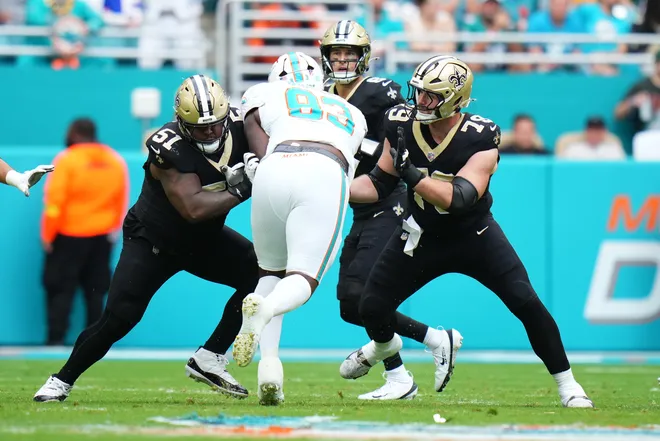 Nov 30, 2025; Miami Gardens, Florida, USA; New Orleans Saints center Cesar Ruiz (51) and center Luke Fortner (79) attempt to block Miami Dolphins defensive tackle Zeek Biggers (93) during the first half at Hard Rock Stadium. Mandatory Credit: Rich Storry-Imagn Images