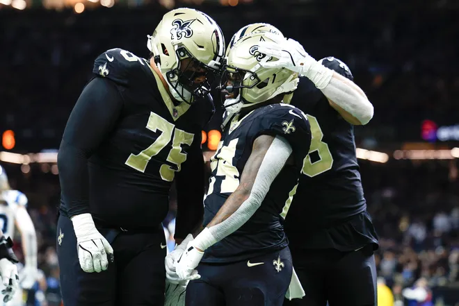 NEW ORLEANS, LOUISIANA - DECEMBER 14: Devin Neal #24 of the New Orleans Saints celebrates with teammate Taliese Fuaga #75 after scoring a touchdown against the Carolina Panthers during the second quarter at Caesars Superdome on December 14, 2025 in New Orleans, Louisiana. (Photo by Sean Gardner/Getty Images)