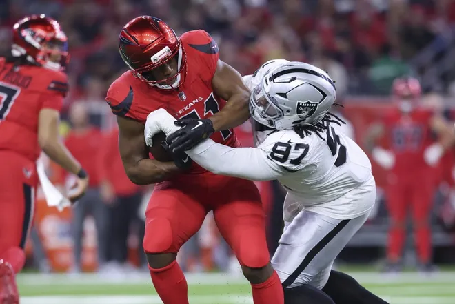 Dec 21, 2025; Houston, Texas, USA; Houston Texans running back Nick Chubb (21) runs with the ball as Las Vegas Raiders defensive tackle Tonka Hemingway (97) makes a tackle during the fourth quarter at NRG Stadium.