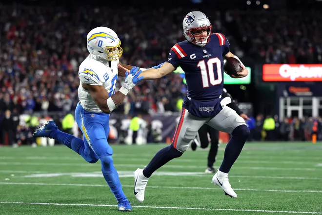 FOXBOROUGH, MASSACHUSETTS - JANUARY 11: Drake Maye #10 of the New England Patriots scrambles with the ball defended by Daiyan Henley #0 of the Los Angeles Chargers during the second quarter of the AFC Wild Card Playoff game at Gillette Stadium on January 11, 2026 in Foxborough, Massachusetts. (Photo by Sarah Stier/Getty Images)