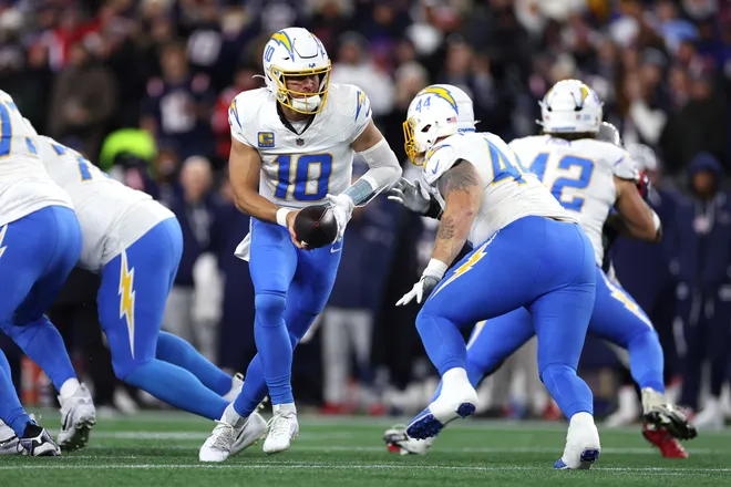 FOXBOROUGH, MASSACHUSETTS - JANUARY 11: Justin Herbert #10 of the Los Angeles Chargers hands the ball to teammate Scott Matlock #44 against the New England Patriots during the first quarter of the AFC Wild Card Playoff game at Gillette Stadium on January 11, 2026 in Foxborough, Massachusetts. (Photo by Sarah Stier/Getty Images)