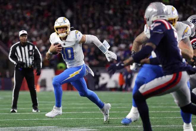 FOXBOROUGH, MASSACHUSETTS - JANUARY 11: Justin Herbert #10 of the Los Angeles Chargers scrambles with the ball against the New England Patriots during the first quarter of the AFC Wild Card Playoff game at Gillette Stadium on January 11, 2026 in Foxborough, Massachusetts. (Photo by Adam Glanzman/Getty Images)