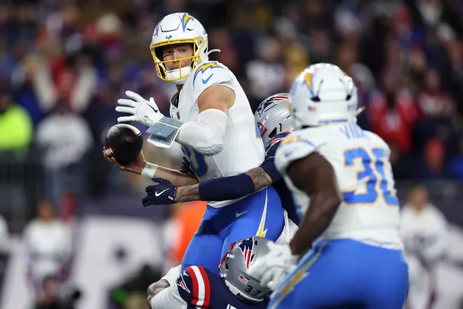 FOXBOROUGH, MASSACHUSETTS - JANUARY 11: Justin Herbert #10 of the Los Angeles Chargers looks to pass the ball under pressure from Anfernee Jennings #33 and Carlton Davis III #7 of the New England Patriots of the AFC Wild Card Playoff game at Gillette Stadium on January 11, 2026 in Foxborough, Massachusetts. (Photo by Sarah Stier/Getty Images)