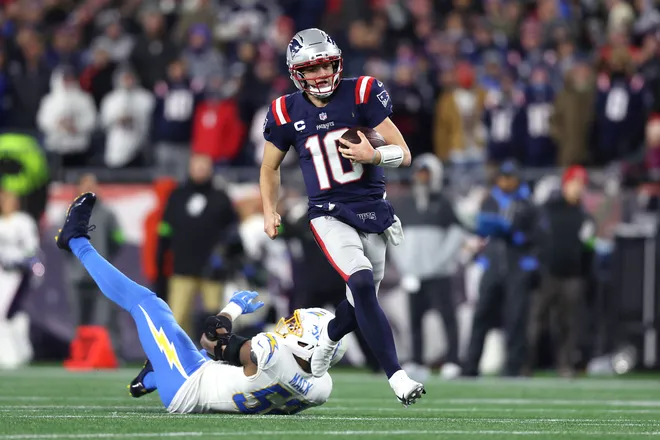 FOXBOROUGH, MASSACHUSETTS - JANUARY 11: Drake Maye #10 of the New England Patriots avoids a tackle Khalil Mack #52 of the Los Angeles Chargers during the second quarter of the AFC Wild Card Playoff game at Gillette Stadium on January 11, 2026 in Foxborough, Massachusetts. (Photo by Adam Glanzman/Getty Images)
