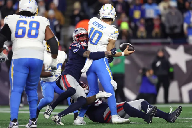 FOXBOROUGH, MASSACHUSETTS - JANUARY 11: Justin Herbert #10 of the Los Angeles Chargers looks to pass the ball under pressure from Carlton Davis III #7 and Anfernee Jennings #33 of the New England Patriots of the AFC Wild Card Playoff game at Gillette Stadium on January 11, 2026 in Foxborough, Massachusetts. (Photo by Adam Glanzman/Getty Images)