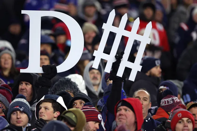 FOXBOROUGH, MASSACHUSETTS - JANUARY 11: Fans hold up signs during the first half of the AFC Wild Card Playoff game between the New England Patriots and the Los Angeles Chargers at Gillette Stadium on January 11, 2026 in Foxborough, Massachusetts. (Photo by Adam Glanzman/Getty Images)