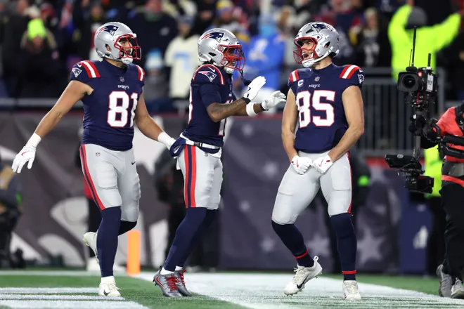 FOXBOROUGH, MASSACHUSETTS - JANUARY 11: Hunter Henry #85 of the New England Patriots celebrates with teammates Austin Hooper #81 and Kyle Williams #18 after a touchdown against the Los Angeles Chargers during the fourth quarter of the AFC Wild Card Playoff game at Gillette Stadium on January 11, 2026 in Foxborough, Massachusetts. (Photo by Adam Glanzman/Getty Images)