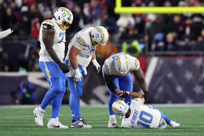 FOXBOROUGH, MASSACHUSETTS - JANUARY 11: Justin Herbert #10 of the Los Angeles Chargers is helped up by teammates after a play against the New England Patriots during the fourth quarter of the AFC Wild Card Playoff game at Gillette Stadium on January 11, 2026 in Foxborough, Massachusetts. (Photo by Adam Glanzman/Getty Images)