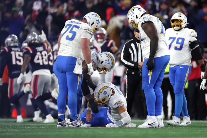 FOXBOROUGH, MASSACHUSETTS - JANUARY 11: Justin Herbert #10 of the Los Angeles Chargers is helped up by teammates after a play against the New England Patriots during the fourth quarter of the AFC Wild Card Playoff game at Gillette Stadium on January 11, 2026 in Foxborough, Massachusetts. (Photo by Sarah Stier/Getty Images)