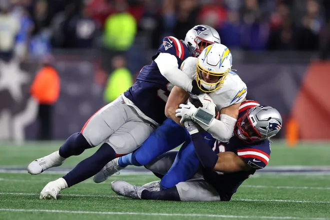 FOXBOROUGH, MASSACHUSETTS - JANUARY 11: Elijah Ponder #91 and Christian Elliss #53 of the New England Patriots tackle Justin Herbert #10 of the Los Angeles Chargers during the fourth quarter of the AFC Wild Card Playoff game at Gillette Stadium on January 11, 2026 in Foxborough, Massachusetts. (Photo by Adam Glanzman/Getty Images)