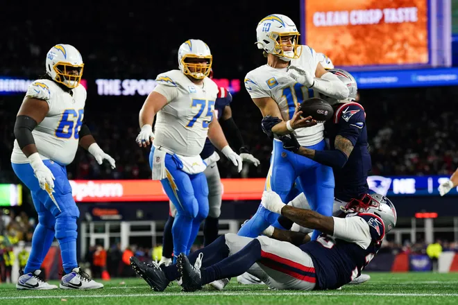 Jan 11, 2026; Foxborough, MA, USA; Los Angeles Chargers quarterback Justin Herbert (10) throws the ball away to avoid a sack during the second quarter against the New England Patriots in an AFC Wild Card Round game at Gillette Stadium. Mandatory Credit: David Butler II-Imagn Images