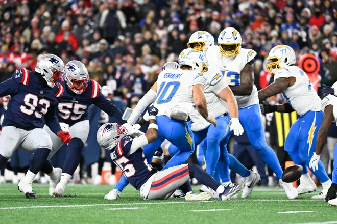 Jan 11, 2026; Foxborough, MA, USA; Los Angeles Chargers quarterback Justin Herbert (10) fumbles after a hit by New England Patriots cornerback Marcus Jones (25) during the third quarter in an AFC Wild Card Round game at Gillette Stadium. Mandatory Credit: Eric Canha-Imagn Images