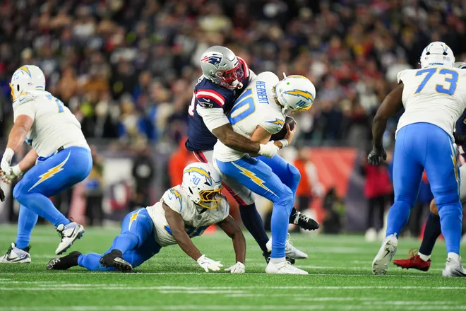 Jan 11, 2026; Foxborough, MA, USA; Los Angeles Chargers quarterback Justin Herbert (10) is sacked by New England Patriots linebacker Anfernee Jennings (33) during the fourth quarter against the New England Patriotsin an AFC Wild Card Round game at Gillette Stadium. Mandatory Credit: David Butler II-Imagn Images