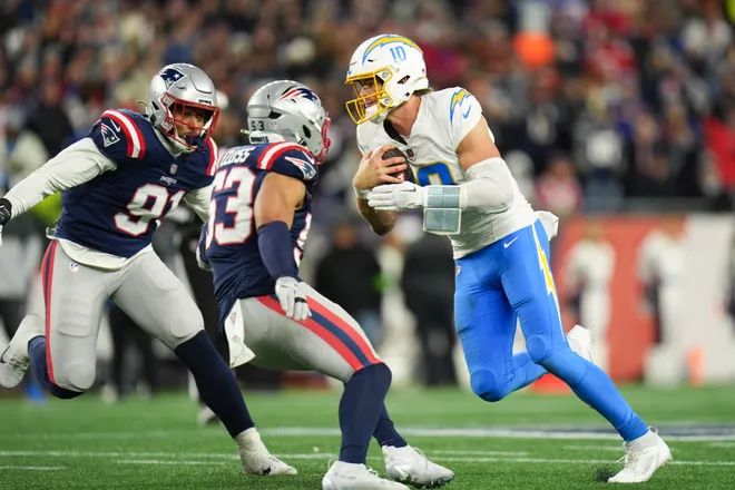 Jan 11, 2026; Foxborough, MA, USA; Los Angeles Chargers quarterback Justin Herbert (10) scrambles as New England Patriots linebacker Elijah Ponder (91) defends during the fourth quarter in an AFC Wild Card Round game at Gillette Stadium. Mandatory Credit: David Butler II-Imagn Images
