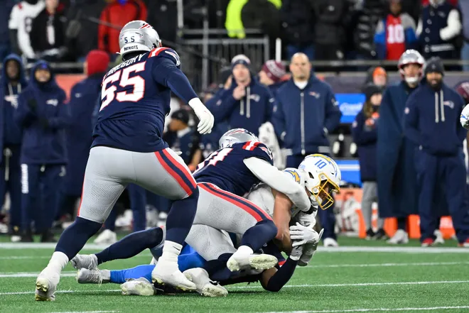 Jan 11, 2026; Foxborough, MA, USA; Los Angeles Chargers quarterback Justin Herbert (10) is brought down by New England Patriots linebacker Elijah Ponder (91) during the second half in an AFC Wild Card Round game at Gillette Stadium. Mandatory Credit: Eric Canha-Imagn Images