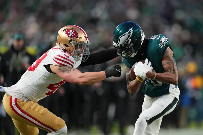 PHILADELPHIA, PENNSYLVANIA - JANUARY 11: Garret Wallow #49 of the San Francisco 49ers tackles DeVonta Smith #6 of the Philadelphia Eagles during the first quarter in the NFC Wild Card Playoff game at Lincoln Financial Field on January 11, 2026 in Philadelphia, Pennsylvania. (Photo by Mitchell Leff/Getty Images)