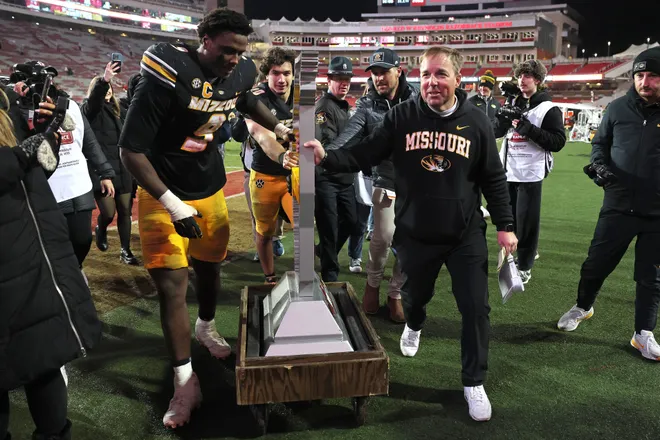 Nov 29, 2025; Fayetteville, Arkansas, USA; Missouri Tigers head coach Eli Drinkwitz celebrates with defensive end Zion Young (9) and the Battle Line trophy after a game against the Arkansas Razorbacks at Donald W. Reynolds Razorback Stadium. Missouri won 31-17. Mandatory Credit: Nelson Chenault-Imagn Images