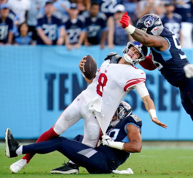 New York Giants quarterback Daniel Jones is being sacked by Tennessee Titans linebacker Rashad Weaver (99) and defensive tackle Jeffery Simmons (98).