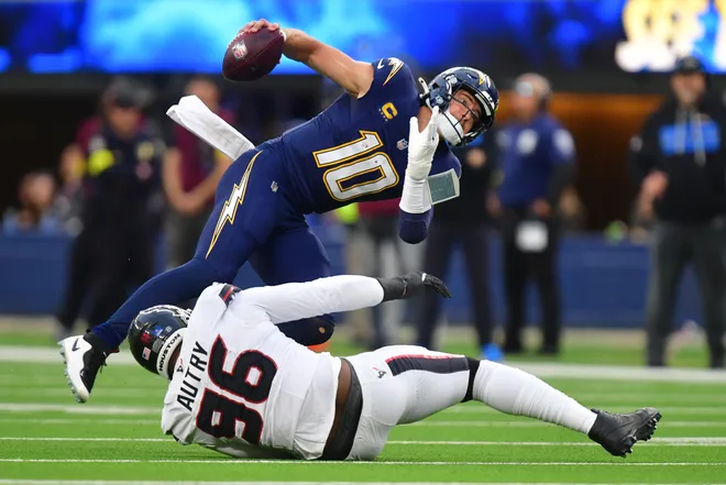 Dec 27, 2025; Inglewood, California, USA; Los Angeles Chargers quarterback Justin Herbert (10) is sacked by Houston Texans defensive end Denico Autry (96) during the first half at SoFi Stadium. Mandatory Credit: Gary A. Vasquez-Imagn Images