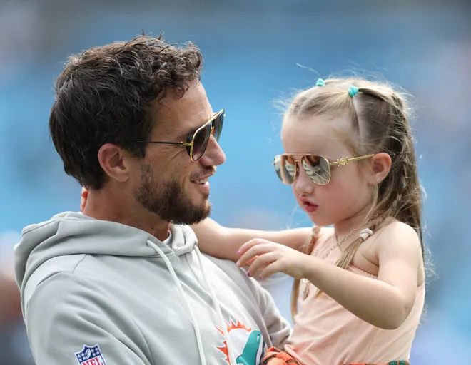 Oct 5, 2025; Charlotte, North Carolina, USA; Miami Dolphins head coach Mike McDaniel holds his daughter Alya June on the sidelines before an NFL game against the Carolina Panthers at Bank of America Stadium. Mandatory Credit: Cory Knowlton-Imagn Images