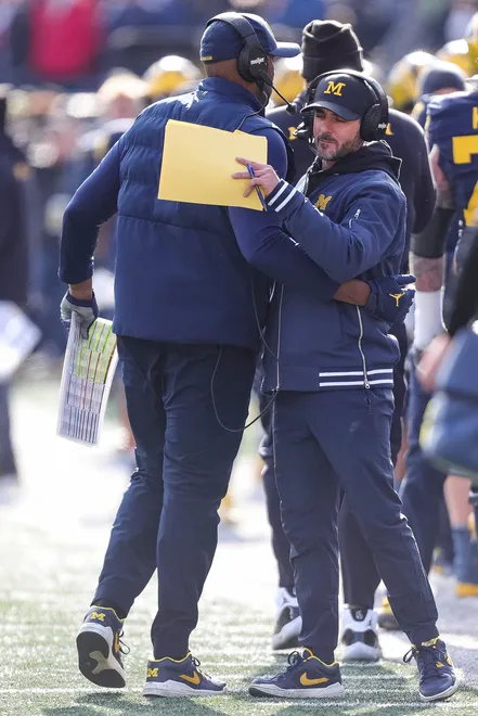 Michigan acting head coach/offensive coordinator Sherrone Moore, left, hugs defensive coordinator Jesse Minter after Will Johnson's interception against Ohio State during the first quarter at Michigan Stadium in Ann Arbor on Saturday, Nov. 25, 2023.