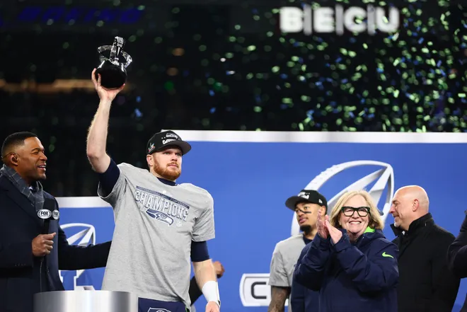 Seattle Seahawks quarterback Sam Darnold celebrates with the trophy on the podium after defeating the Los Angeles Rams in the 2026 NFC Championship Game.