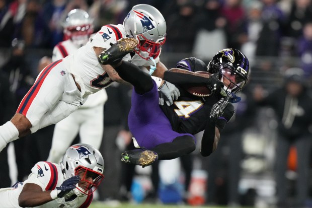 Baltimore Ravens wide receiver Zay Flowers (4) is tackled by New England Patriots cornerback Christian Gonzalez, left, and safety Jaylinn Hawkins during the first half of an NFL game on Sunday, Dec. 21 in Baltimore. (AP Photo/Stephanie Scarbrough)