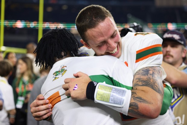 Miami quarterback Carson Beck, right, is hugged by former NFL player Michael Irvin following the Cotton Bowl College Football Playoff quarterfinal game against Ohio State Wednesday, Dec. 31, 2025, in Arlington, Texas. (AP Photo/Gareth Patterson)
