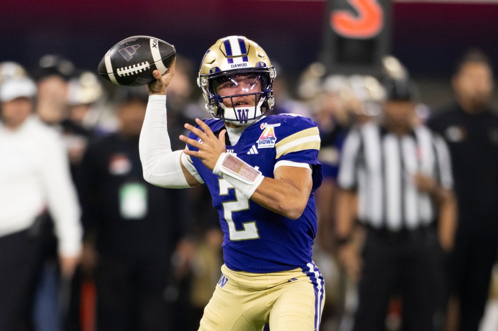 A Boise State Washington football player in a purple jersey and gold helmet throwing a football.