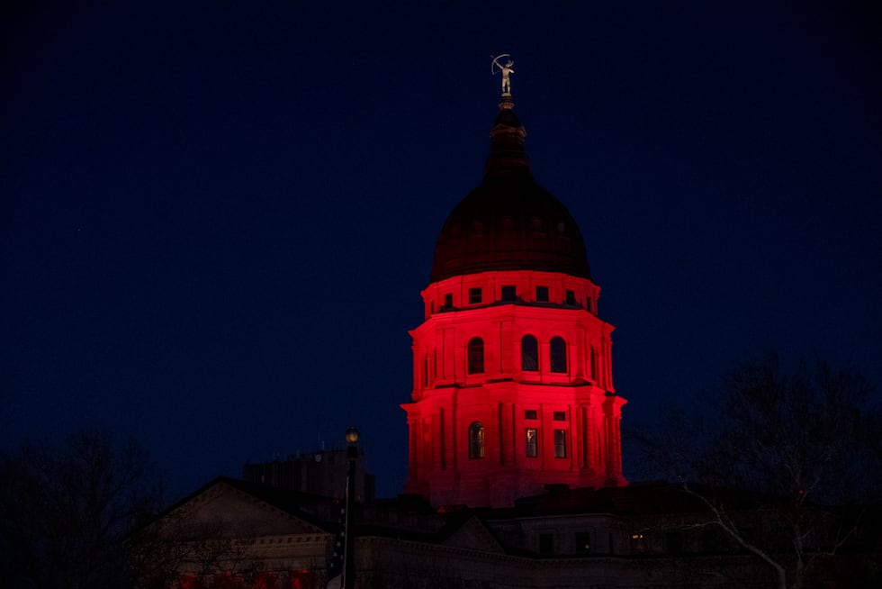 The State Capitol in Topeka, Kan., shines with red light on Monday, Dec. 22, 2025, as they...