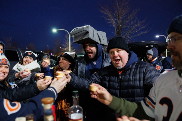 Rob Moore takes a shot of Chick-fil-A sauce while wearing a cheese grater hat while tailgating before the Chicago Bears play the Green Bay Packers in a NFC wild-card game at Soldier Field Jan. 10, 2026, in Chicago. (Armando L. Sanchez/Chicago Tribune)