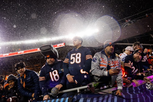 Fans stand in the snow while watching players warm up before the Chicago Bears play the Green Bay Packers in a NFC wild-card game at Soldier Field Jan. 10, 2026, in Chicago. (Armando L. Sanchez/Chicago Tribune)