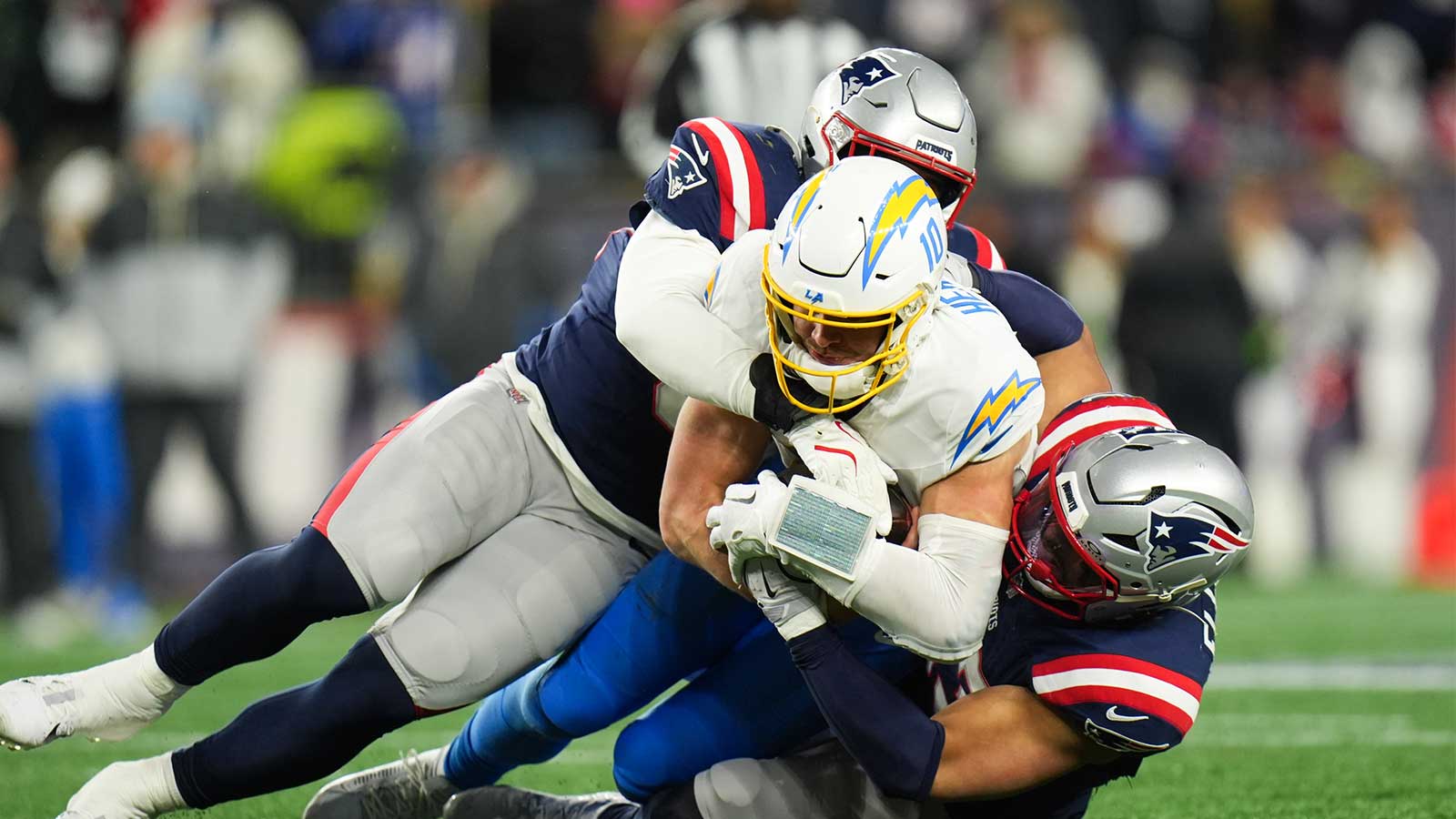 Jan 11, 2026; Foxborough, MA, USA; Los Angeles Chargers quarterback Justin Herbert (10) is tackled by New England Patriots linebacker Elijah Ponder (91) during the fourth quarter in an AFC Wild Card Round game at Gillette Stadium. Mandatory Credit: David Butler II-Imagn Images