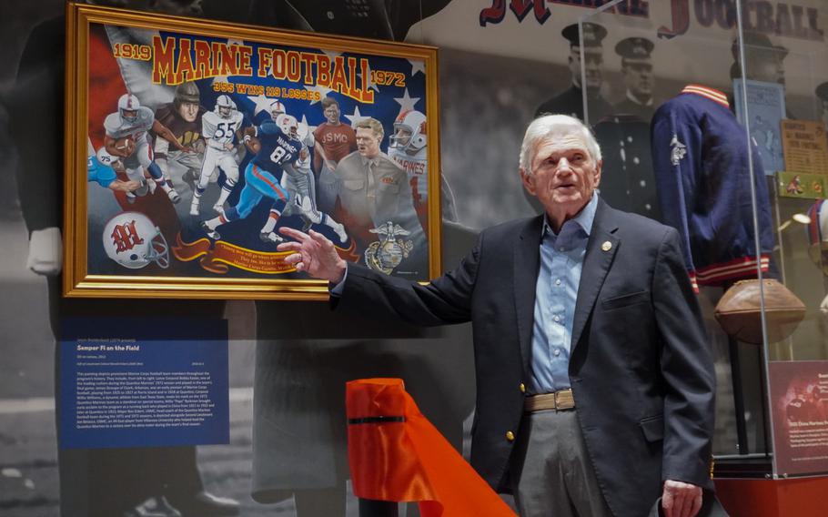 A man points at a “Marine Football” painting.