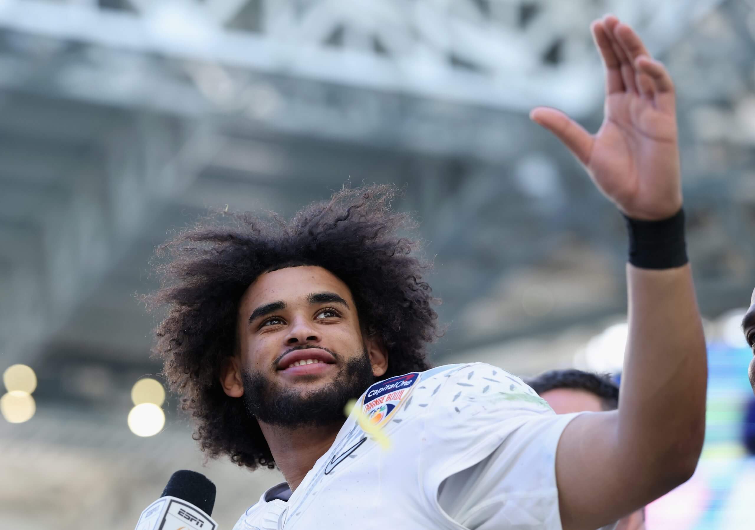 Dante Moore looks off with his hand up.