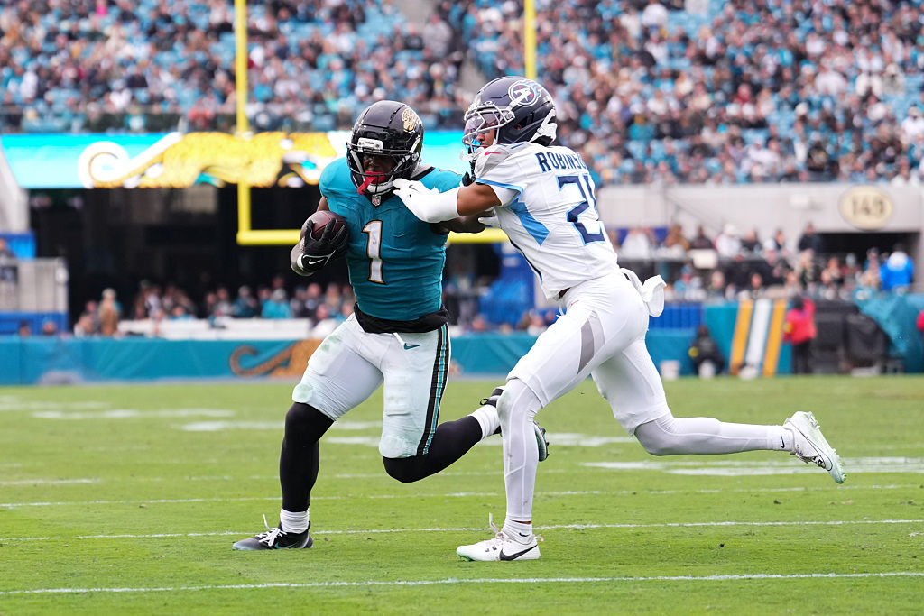 JACKSONVILLE, FLORIDA - JANUARY 04: Travis Etienne Jr. #1 of the Jacksonville Jaguars runs the ball against Micah Robinson #21 of the Tennessee Titans during the second half at EverBank Stadium on January 04, 2026 in Jacksonville, Florida. (Photo by Rich Storry/Getty Images)