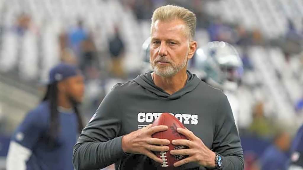 Matt Eberflus, Dallas Cowboys defensive coordinator, wearing a gray shirt and holding a football. Helped lead the team to a historically bad season and a top pick in the draft. 