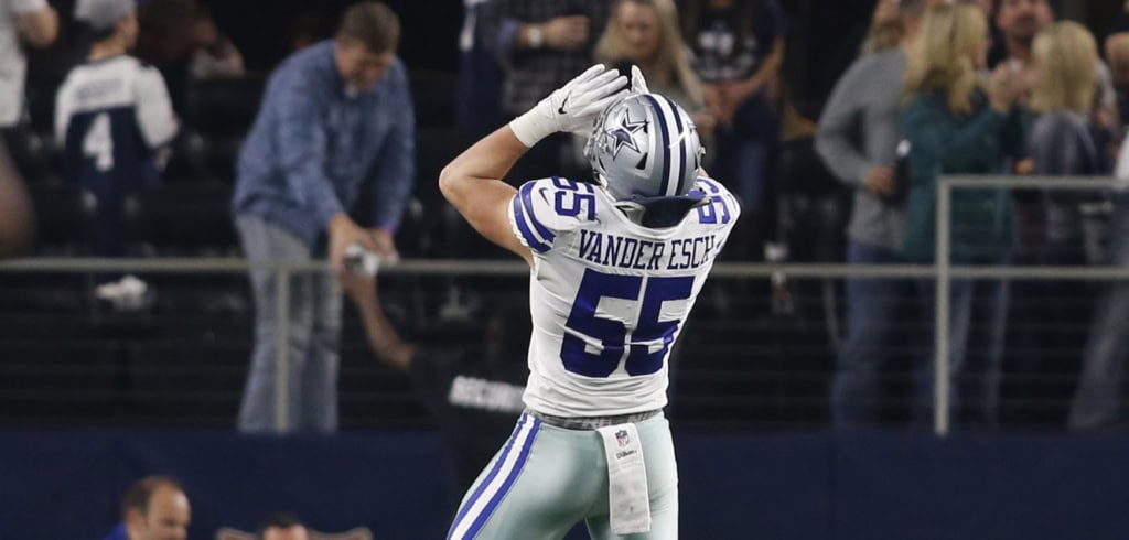 Dallas Cowboys linebacker Leighton Vander Esch raises his arms toward the crowd while wearing a white Cowboys uniform during a game.