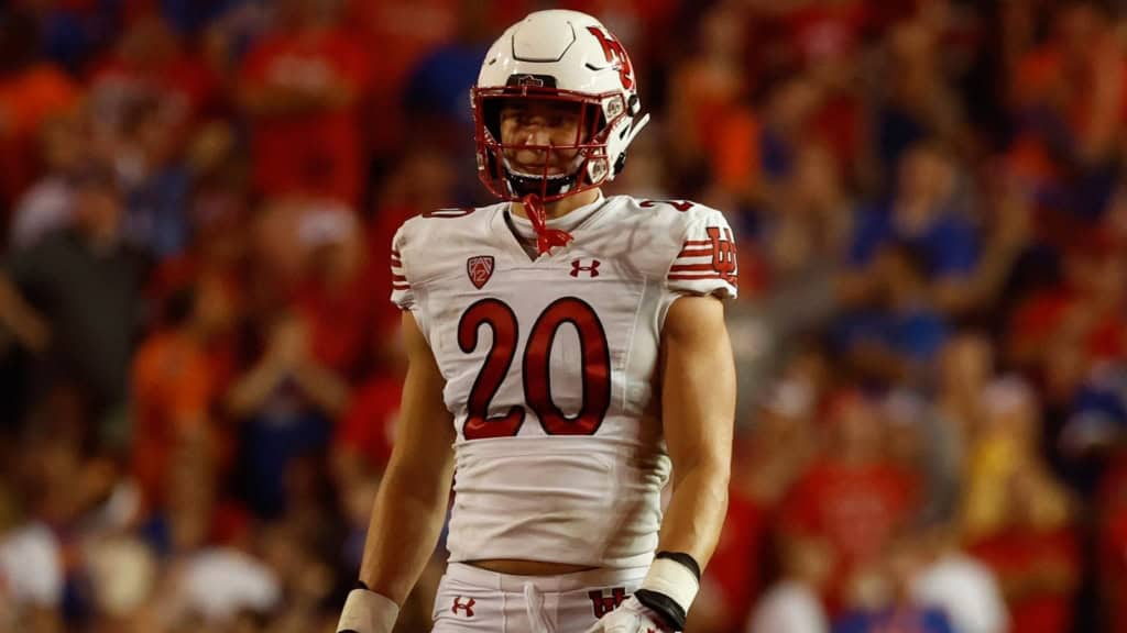 Utah Utes player, Landry Barton, wearing a white No. 20 jersey stands on the field under stadium lights during a night game.