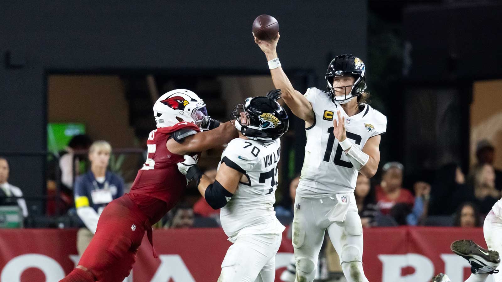 Jacksonville Jaguars quarterback Trevor Lawrence (16) throws a pass as offensive lineman Cole Van Lanen (70) blocks Arizona Cardinals linebacker Zaven Collins (25) at State Farm Stadium.