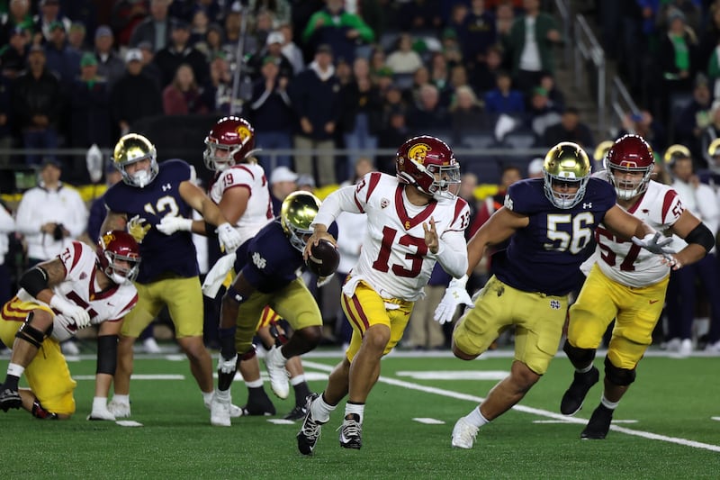 Williams (13) scrambles with ball in hand and is pursued by Notre Dame defenders.